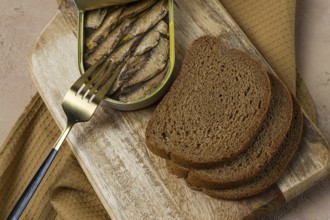 Sprats in butter, with black bread, canned smoked fish, open, close-up, top view, no people