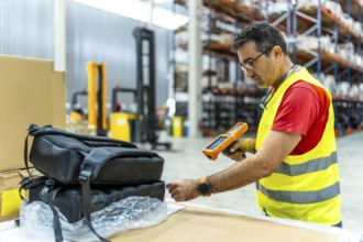 Man taking inventory using scanner to read barcode of products in a warehouse