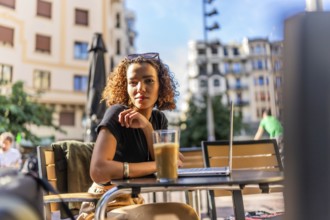 Beauty young arab woman drinking coffee using laptop in an outdoor cafeteria