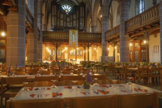 Several laid tables in a warmly lit church with organ in the background, Vesperkirche Calw, Black