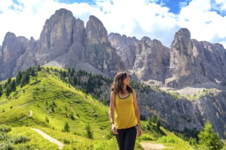 Woman enjoying a sunny summer day while walking through the picturesque dolomites at gardena pass,