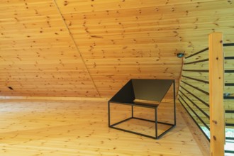 Black metal sitting chair and tubular railings with wooden post in home office set-up on mezzanine
