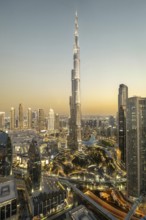 An impressive view of the Burj Khalifa at dusk, surrounded by the twinkling lights of the modern