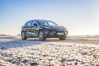 Black car on slightly icy ground under a bright morning sky, Deer E- Carsharing vehicle MG4, Calw