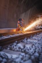 Night-time welding in the tunnel with flying sparks and protected workers, rail welding, track