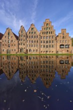 Historic salt warehouses, brick buildings reflected on the water surface of the Trave, blue sky