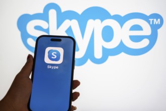 In this photo illustration, a person holds a mobile phone displaying Skype application, in