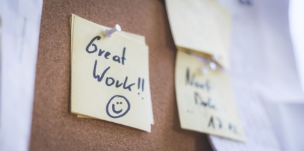 Close up of pinned note ?Great work? on cork board