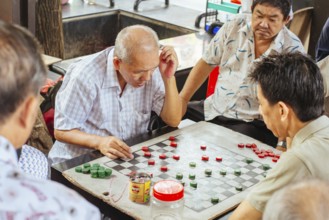 Chinatown, Singapore, June 21st 2015: Older Chinese men play Xiangqi, or Chinese Chess in a public