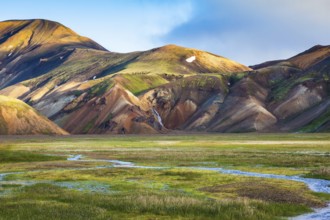 Green Valley is flooded with melt water. Snow lies in the hollows of colorful rhyolite mountains.