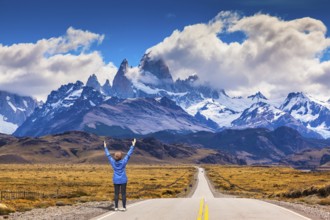 Woman delighted natural beauty raised her hands. The highway leads to the snow-capped peaks of
