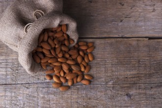 Almonds in a sack on old wooden board