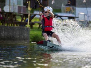 Boy or girl with wakeboard, fast ride on the water, water sports, water skiing in the wakepark