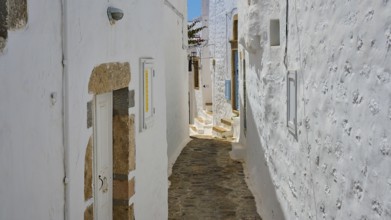 Narrow, stony corridor between white-painted houses with shutters, bright daylight, Chora, Old