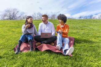 Three young entrepreneurs working outdoors, using technological devices, enjoying a sunny spring