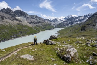 Mountaineer on a hiking trail at a blue mountain lake, reservoir Lac des Dix, behind mountain peak