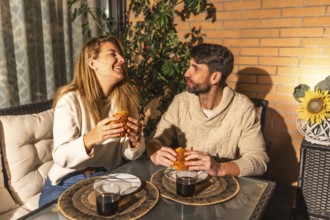 Smiling man and woman sharing a meal of burgers and drinks, creating a warm and intimate atmosphere