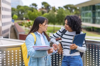 Two multi-ethnic female students reading and commenting notes standing outside the campus