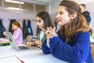 Smart young female students thinking and learning using laptop computer and notebook in elementary