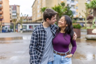 Young multiethnic couple sharing a joyful moment outdoors in a vibrant urban setting, showcasing