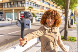 Latin female beuty and young vlogger streaming online sitting on urban stairs in a sunny autumn day