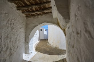 Arched passageway with wooden ceiling and white walls in a historic building, Chora, main town of