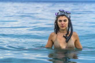 Young woman wearing snorkeling gear, swimming in the crystal clear waters of white beach, moalboal,