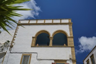 White building with arches and columns under a bright blue sky, Mediterranean, Chora, main town