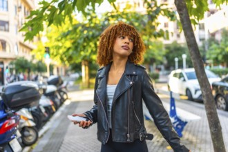 Side view of a beauty millennial latin woman listening to music walking along a city