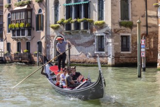 Venetian gondola with gondolier travelling on the canals of Venice, Venice, Italy, Europe