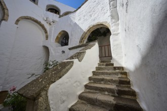 Stone staircase in a historic building with white walls and stone arches on a sunny day, Inside the