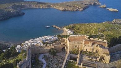 Drone shot, Lindos, late afternoon light, drone view of an old windmill on a rocky shore in the