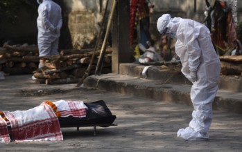 Family members wearing PPE kit performing last rites of a person who died of COVID-19 coronavirus