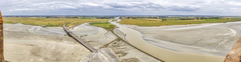 Extensive river landscape with sandbanks and green meadows under a cloudy sky, Le Mont-Saint-Michel