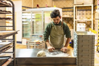 Male latin baker kneading dough alone in the kitchen of an artisan bakery workshop