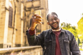 Happy and smiling african man enjoying walking along the city taking photos relaxed