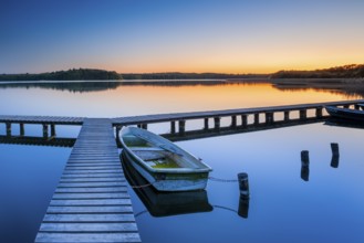 Wooden jetty with rowing boat at dusk, sunset on Lake Schaalsee, Mecklenburg-Western Pomerania,