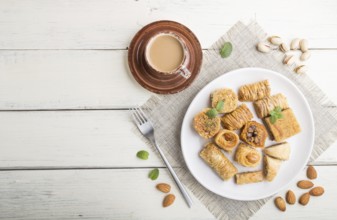 Traditional arabic sweets (kunafa, baklava) and a cup of coffee on a white wooden background and