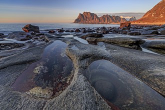 Rocky coast in front of steep mountains in the evening light, winter, the eye, Utakleiv,
