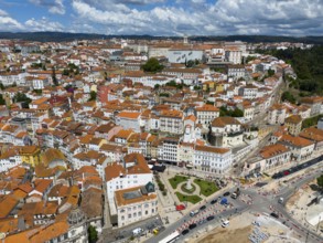 City view with red tiled roofs, densely built-up buildings and a blue sky with clouds, aerial view,