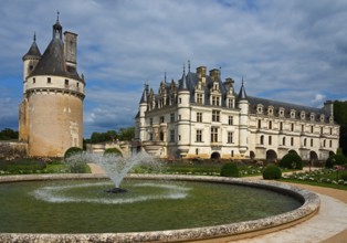 Castle with round tower and fountain in a well-tended garden under a blue sky, Chenonceau Castle,