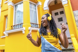 Low angle view photo of a cool african young woman dancing listening to music in the street outside