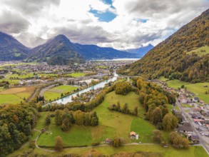 Panoramic view of a mountain landscape with meadows, river and a village under a cloudy sky,