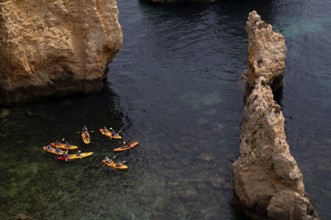 Kayaker, kayaks, kayaking, guided tour through grottos, rocks in the sea, Ponta da Piedade, Lagos,