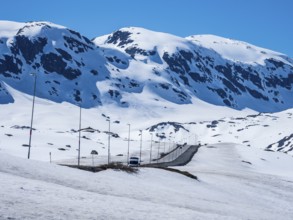 Camper van driving through snowy high mountain landscape, Haukelivegen road, E134, Norway, Europe