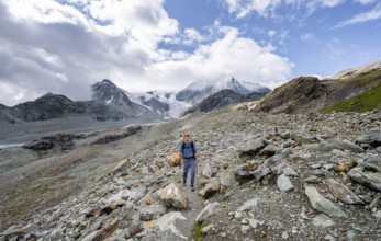 Mountaineer on a hiking trail, behind glacier Glacier de Cheilon and summit Mont Blanc de Cheilon,