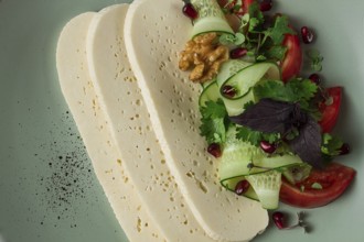 Sliced Imeruli cheese, Georgian cheese, with vegetables, top view, no people