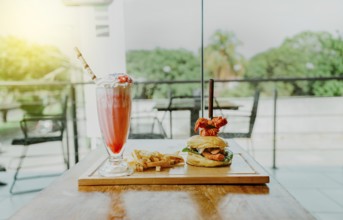 Delicious chicken burger with french fries and strawberry milkshake on restaurant table. Hamburger
