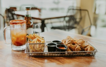 Delicious spicy chicken wings with fries and michelada accompanied by beer served on a restaurant