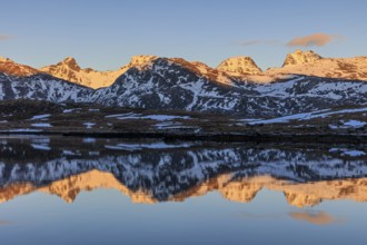 Steep mountains reflected in fjord, evening light, snowy, winter, Moskenesoya, Lofoten, Norway,